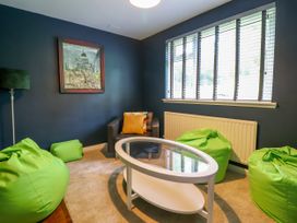 A sitting room with green bean bag chairs a glass coffee table and a dark armchair at The Wardens House in Tregynon near Newtown