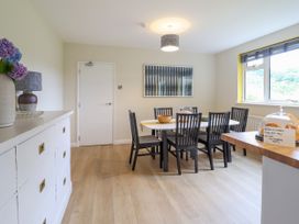 A dining room with a table and six chairs near a window and a sideboard with flowers at The Wardens House in Tregynon near Newtown