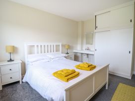 A bedroom with a white bed frame two yellow towels on the bed two matching bedside tables with lamps a sink and a wardrobe at The Wardens House in Tregynon near Newtown