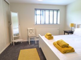 A bedroom with a bed with yellow towels a chair a standing mirror a bedside table with a lamp and a window at The Wardens House in Tregynon near Newtown