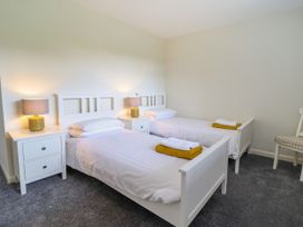 A bedroom with two white beds two white nightstands with lamps and a chair at The Wardens House in Tregynon near Newtown