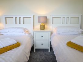 A bedroom with two single beds and a nightstand with a lamp between them at The Wardens House in Tregynon near Newtown