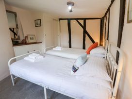A bedroom with two beds and a wardrobe at Rhubarb Cottage Ufford near Woodbridge