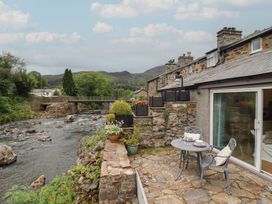 An outdoor patio area with a table and chairs at Riverside Cottage in Beddgelert