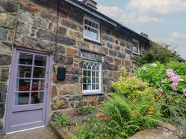 A stone wall with a front door and windows at Riverside Cottage in Beddgelert