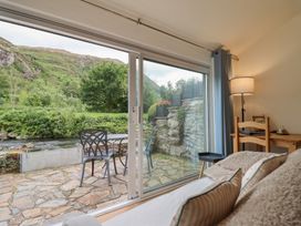 A living room with a view of a river and mountains at Riverside Cottage in Beddgelert