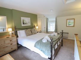 A bedroom with a bed, nightstand, and window at Riverside Cottage in Beddgelert