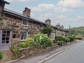 A stone house with plants by the door near the road at Riverside Cottage in Beddgelert