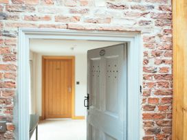 An open white wooden door in a brick wall leading to a hallway with a wooden door at Servant's Quarters Bolton Percy near Tadcaster
