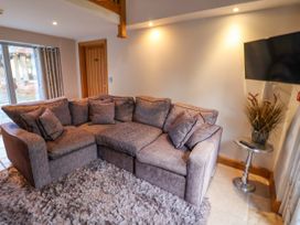 A living room with a sectional sofa a shaggy rug a side table with a plant and a wall-mounted TV at Servant's Quarters in Bolton Percy near Tadcaster