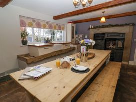 A kitchen with a wooden dining table set with glasses of orange juice a teapot and flowers near a window and an old fireplace at Servant's Quarters Bolton Percy near Tadcaster