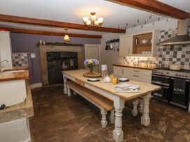 A kitchen with wooden beams on the ceiling a large wooden table with benches a stove an oven and cabinets at Servant's Quarters Bolton Percy near Tadcaster