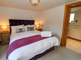A bedroom with a bed with folded towels bedside tables with lamps and an open door to a bathroom at Servant's Quarters Bolton Percy near Tadcaster