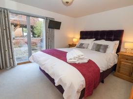 A bedroom with a double bed with white bedding and purple throw with bedside tables and lamps at Servant's Quarters Bolton Percy near Tadcaster