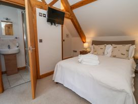 A bedroom with a double bed and two bedside tables with lamps and an open door to a bathroom at Servant's Quarters Bolton Percy near Tadcaster