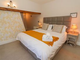 A bedroom with a double bed with beige cushioned headboard bedside tables with lamps and folded towels on the bed at Servant's Quarters Bolton Percy near Tadcaster
