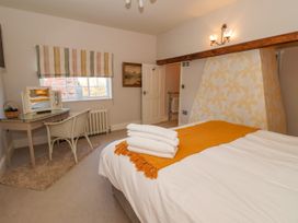 A bedroom with a bed folded towels and a yellow throw a desk chair window and a door at Servant's Quarters Bolton Percy near Tadcaster
