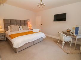 A bedroom with a double bed two bedside tables lamps a wall-mounted tv a desk and a chair at Servant's Quarters Bolton Percy near Tadcaster
