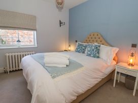 A bedroom with a bed with blue cushions and white towels on it and a bedside table with a lamp at Servant's Quarters in Bolton Percy near Tadcaster