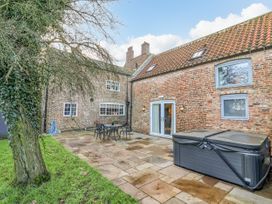An outdoor patio with a table and chairs a hot tub and brick walls at Servant's Quarters Bolton Percy near Tadcaster