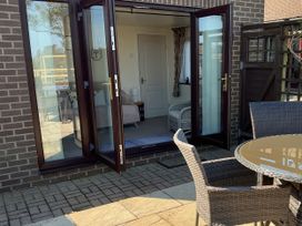 An outdoor area with a table and chairs beside glass doors at Penn Lea in Penally
