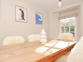 A dining room with a wooden table and white chairs at Mermaid Cottage in Port Isaac