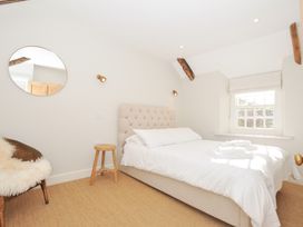 A bedroom with a bed and a chair at Mermaid Cottage in Port Isaac