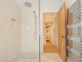 A shower area with glass door and towel radiator at Mermaid Cottage in Port Isaac