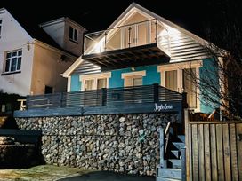 A two-story house with blue and white exterior lighting and stone foundation at Ingledene in Brixham