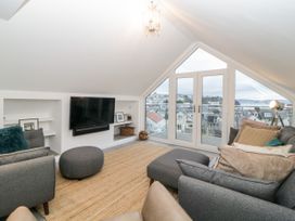 A living room with grey sofas a tv mounted on the wall and a large window overlooking rooftops at Ingledene in Brixham