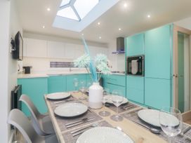 A kitchen with turquoise cabinets a dining table set with plates glasses and a white vase with flowers at Ingledene in Brixham