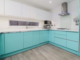 A kitchen with teal lower cabinets and white upper cabinets with a window above the sink at Ingledene in Brixham