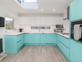 A kitchen with turquoise lower cabinets white upper cabinets and wooden floor at Ingledene in Brixham