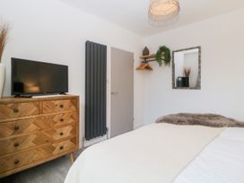 A bedroom with a wooden dresser supporting a television a grey radiator and a bed with blankets at Ingledene in Brixham