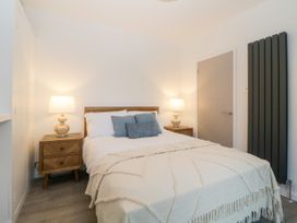 A bedroom with a bed two bedside tables with lamps and a tall radiator at Ingledene in Brixham
