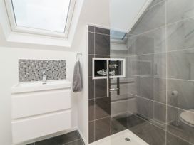 A bathroom with a white sink, mosaic tile backsplash, gray tiled shower with glass door and a skylight at Ingledene Brixham