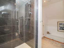 A bathroom with a glass shower enclosure and a white bathtub with a framed picture on the wall at Ingledene in Brixham