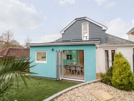 Backyard view of a house with a turquoise extension featuring open folding doors revealing a dining table with chairs at Ingledene in Brixham