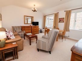 A living room with striped armchairs a brown sofa wooden coffee table and dining table with chairs at 6 Granary Court in York