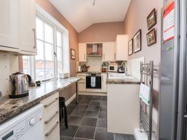A kitchen with marble countertops white cabinets and tiled floor at 6 Granary Court in York