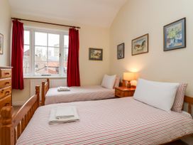 A bedroom with two single beds a wooden chest of drawers red curtains and framed pictures on the wall at 6 Granary Court in York