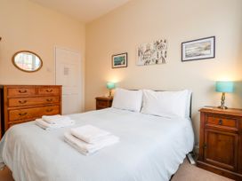 A bedroom with a double bed white bedding wooden bedside tables and dresser at 6 Granary Court in York