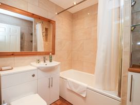 A bathroom with a sink, toilet, bathtub with shower curtain, and a large mirror at 6 Granary Court York