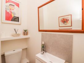 A bathroom with a toilet under a white shelf holding a plant and diffuser next to a sink with a mirror above at 6 Granary Court in York