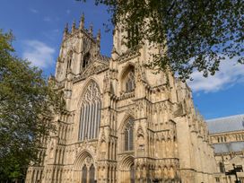 The exterior of a large Gothic-style cathedral with pointed arches and detailed stonework partially covered by tree branches at 6 Granary Court in York