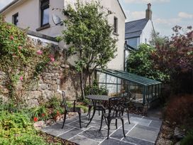 A garden with a table and chairs near a greenhouse at The Cottage on The Square in Chagford