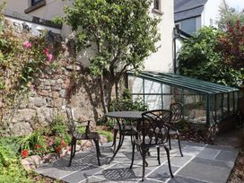 A garden with a table and chairs next to a greenhouse at The Cottage on The Square in Chagford