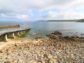 A pier extending into water with rocks at the shore at Harbour Studio in Sennen Cove