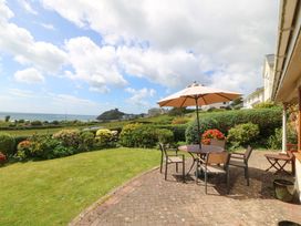 A garden with a table and chairs under an umbrella at Cwm Eilir in Criccieth