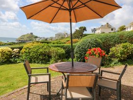 An outdoor table and chairs with flowers in the background at Cwm Eilir in Criccieth